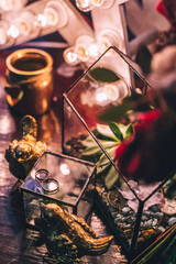 Gold wedding ring looks beautiful on the glass surface on the background of red wedding bouquet