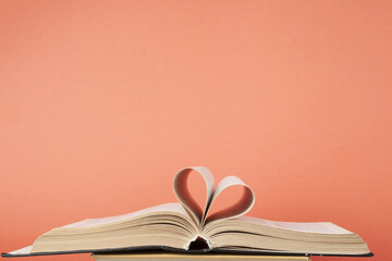 Heart from book page on red background.