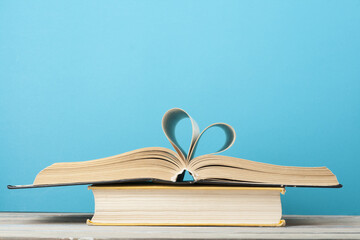 Heart from book page on blue background.