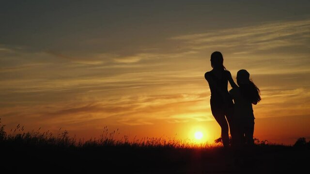 Two Friends Hold Hands And Spin In Circles In A Beautiful Summer Day At Sunset