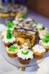Cupcakes decorated with white glaze and snowmen served on glass plate