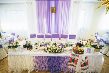 Long dinner tables for wedding couple decorated with violet and white cloth