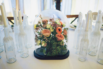Bouquet of roses stands under glass cover on dinner table