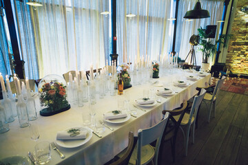 Long dinner table with white and wooden chairs stands in the hall