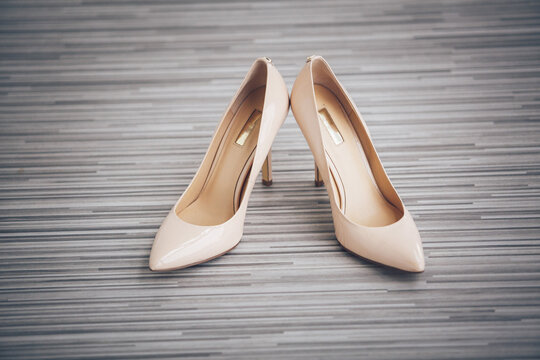 Elegant beige shoes stand on grey floor