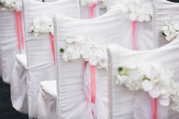 White flowers pinned to back of white chairs