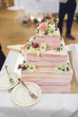 Obraz na płótnie Canvas Square tired wedding cake decorated with pink flowers and pink cream