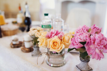 Little bouquets of orange and pink flowers stand on the dinner table