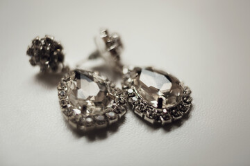 Rich crystal earrings lie on white table