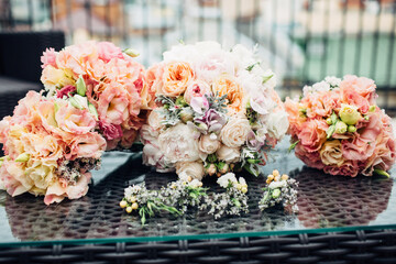 Bouquets of peonies and white flowers lie on glass table outside