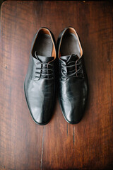 Black leather shoes stand on wooden floor