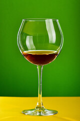 Glass of brown alcoholic beverage standing on yellow surface