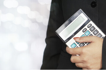 business woman in black suit standing with calculator in hand, tax season or financial concept 