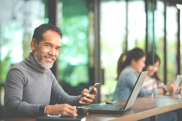 Portrait Smiling Attractive mature man with white stylish short beard using smartphone. Serving...