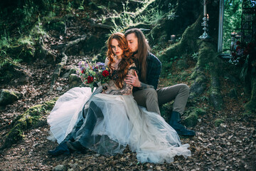 Beautiful young couple together, man with tattoo nad long hair hugging woman in love near old tree. Fairytale concept.
