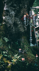 Decorative lanterns and vases with candles in dark red colors stand on green lawn and ground. Advertising concept.