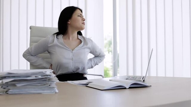 Woman have back pain after sitting all day in office