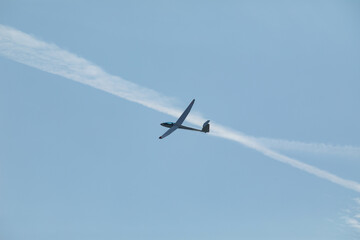 A glider flying in the blue sky ejects the water before the landing.