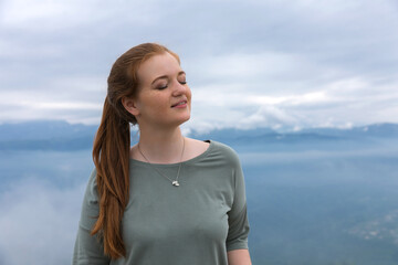 Natural makeup girl with closed eyes smiling in the blue mountains