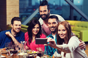 friends taking selfie by smartphone at restaurant