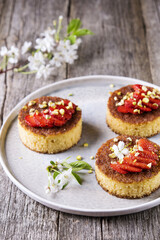 Pieces of homemade semolina cake with strawberry and pistachio decorated flowers of cherry on a rustic vintage wooden table. Selective focus 