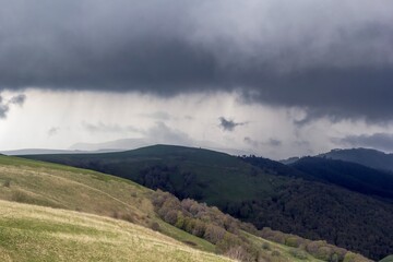 Горный пейзаж, красивый вид на зеленые холмы, пасмурное небо в облаках, панорама горной местности, дикая природа Северного Кавказа