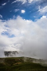 Fototapeta na wymiar Густой туман, зеленые склоны затянутые белыми облаками, живописный пейзаж