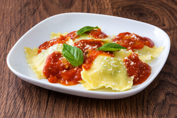 Ravioli with tomato sauce and basil on wooden background. 
