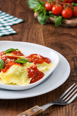 Ravioli with tomato sauce and basil on wooden background. 
