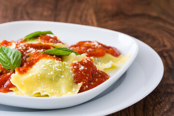 Ravioli with tomato sauce and basil on wooden background. 
