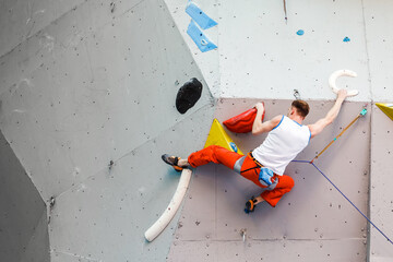 Male Climber sportsman hanging on artificial Climbing Wall, Competition in difficulty contest