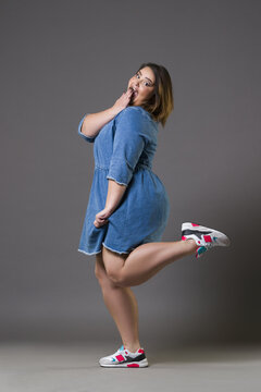 Plus size fashion model in casual clothes, fat woman on gray background, overweight female body