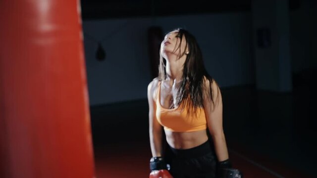 Young tired woman boxer in a dark hall