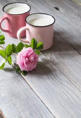 Two pink cups with milk on a white wooden table