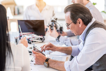 Obraz premium Concentrated mature man working with his team in office