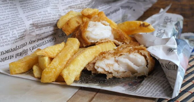 Adding salt and vinegar on an English fish and chips wrapped in newspaper, the traditional way