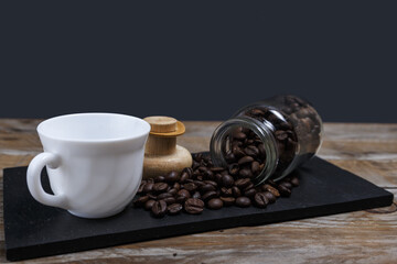 Coffee beans coming out of the jar next to a rate and on a slate tray
