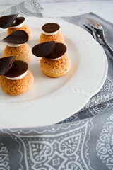 Choux with cream and chocolate. Small cakes with chocolate.