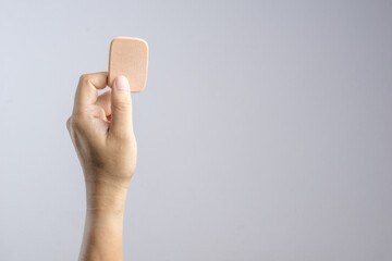 Hand holding brown face sponge