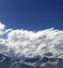 Winter mountain in evening and sunlight silhouette of parachutist