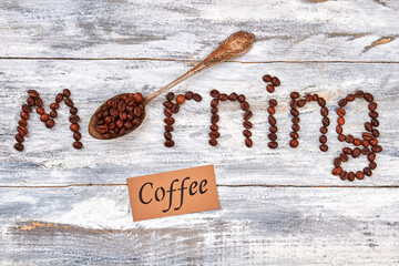 Old vintage spoon, coffee beans. Text morning on wooden background.
