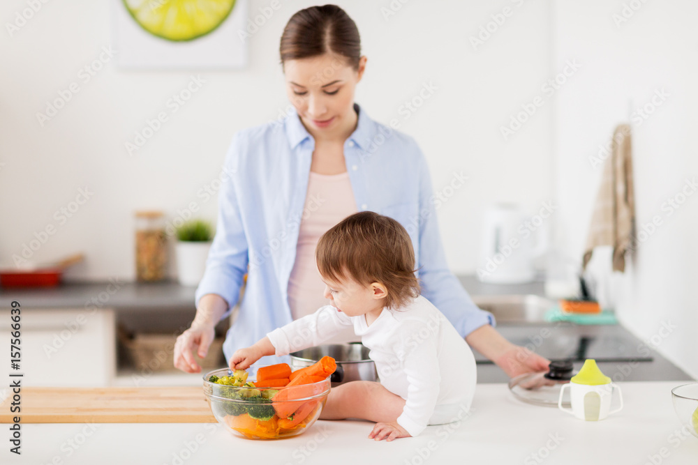 Wall mural happy mother and baby with food at home kitchen