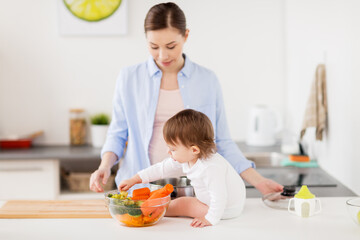 happy mother and baby with food at home kitchen
