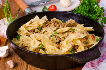 Pasta farfalle with fried meat, mushrooms and vegetables