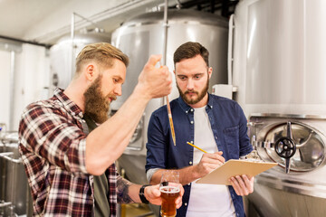 Fototapeta na wymiar men with pipette testing craft beer at brewery