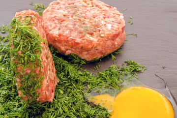Raw cutlet for hamburger in chopped dill.