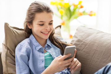smiling girl texting on smartphone at home