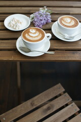 Two cups of cappuccino on a wooden table.
