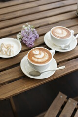 Two cups of cappuccino on a wooden table.