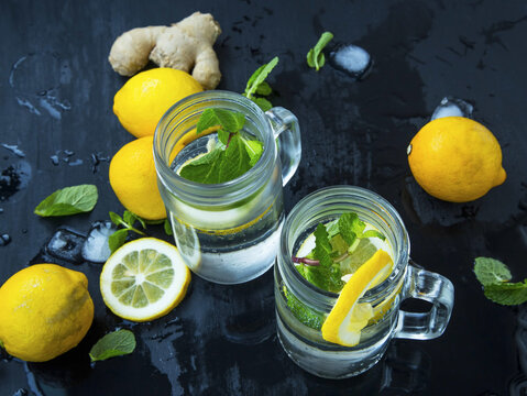 Fresh mojito cocktails glasses with fresh mint and lemons on dark wooden background